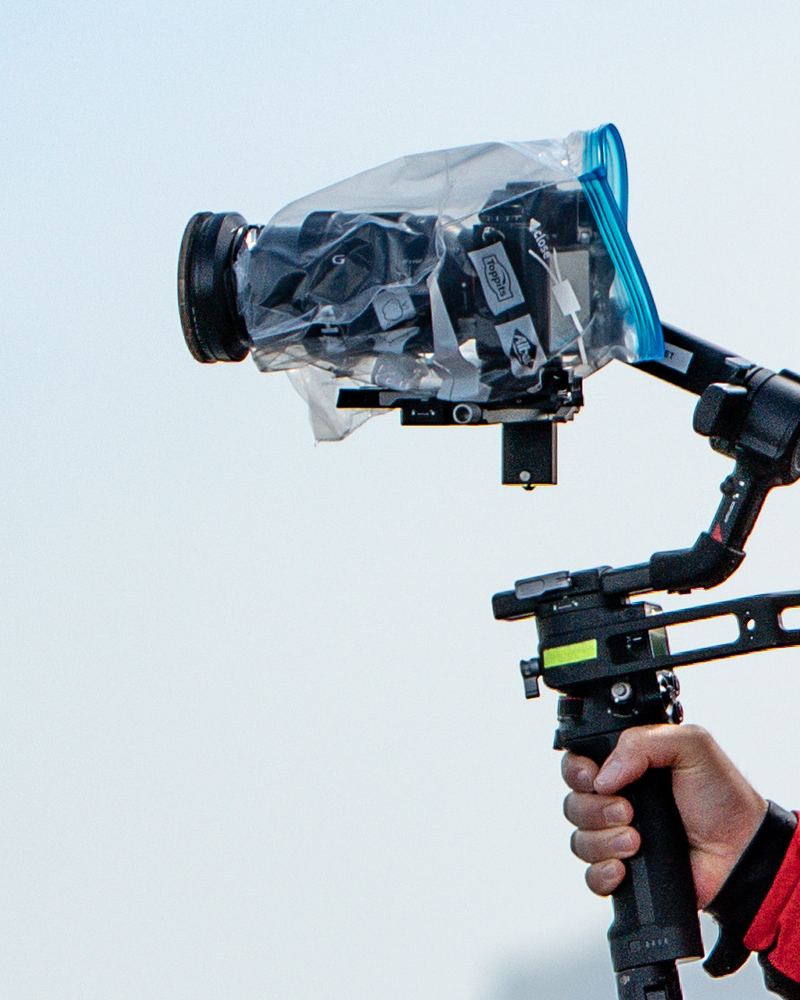Kamera im Regenschutz auf einem Gimbal, gehalten von einer Hand