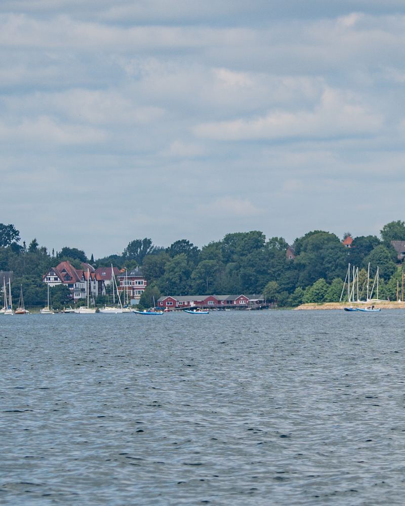 Segelyachten im Hafen am Ufer, davor offenes Wasser